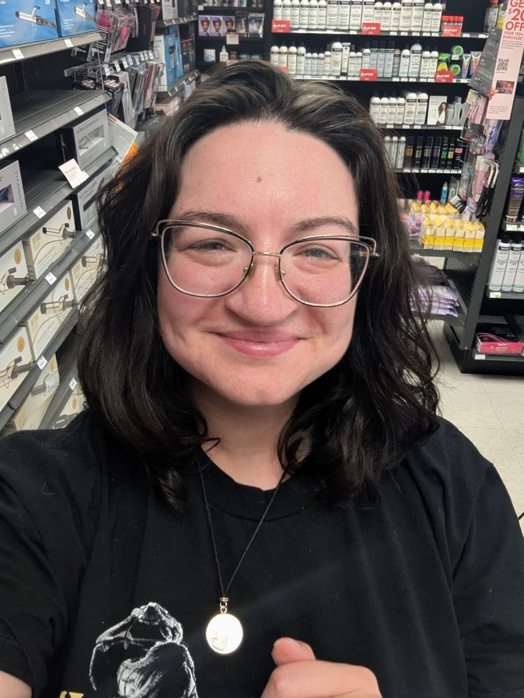 selfie of a white woman in glasses, with wavy dark brown hair cut to her collarbone