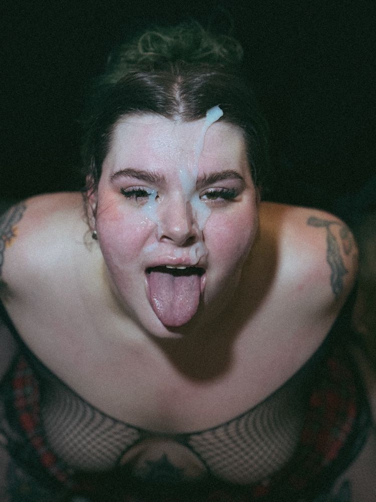 Bratty on her knees with her tongue out and face covered in cum