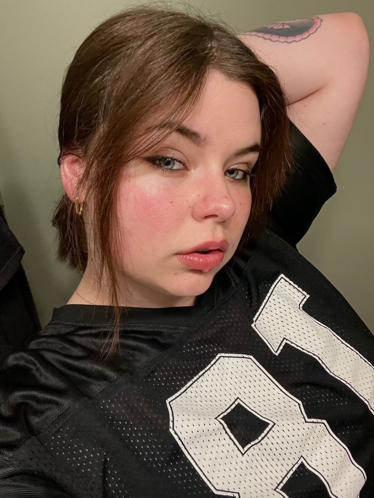 Selfie of me in my Tate McRae jersey. I’m holding my hair up to show my gold hoops