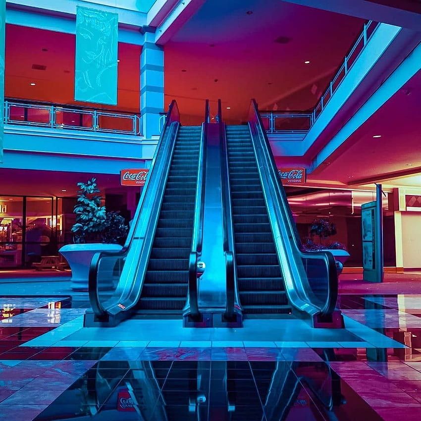 neon lit escalator in an empty mall