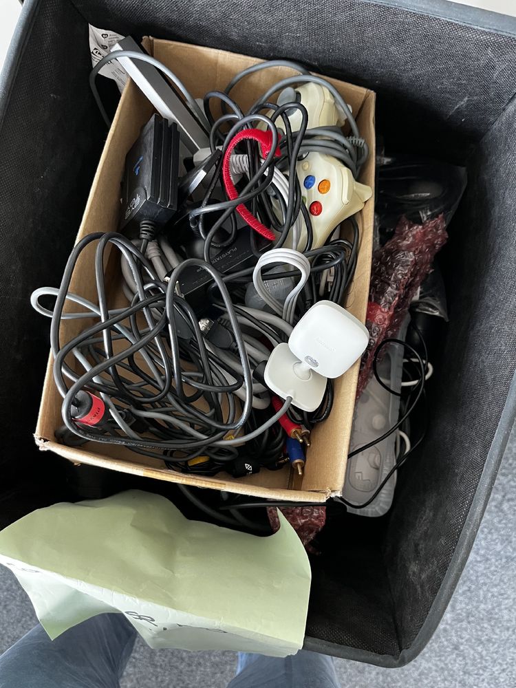 Kiste voller Controller, Konsolen-Zubehör und Kabeln. 