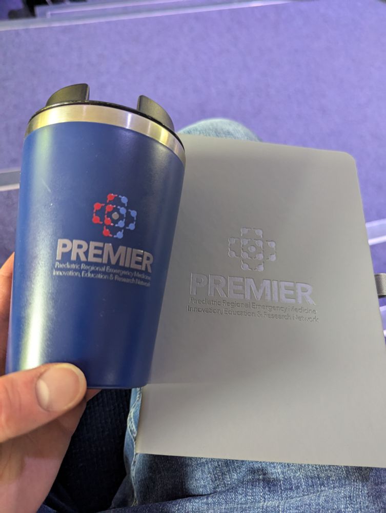 A PREMIER branded coffee cup and notebook 