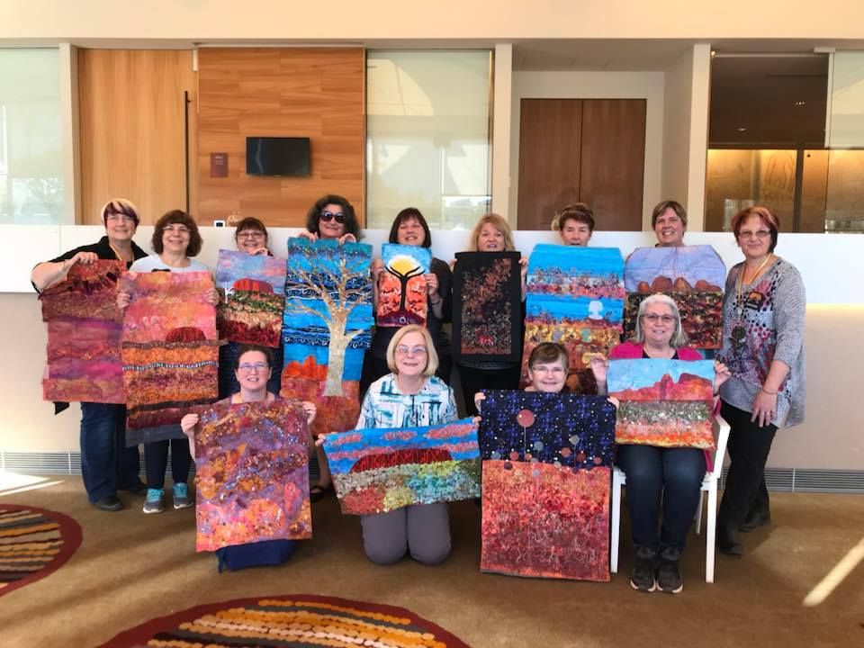 A group of women showing off their desert landscape quilts