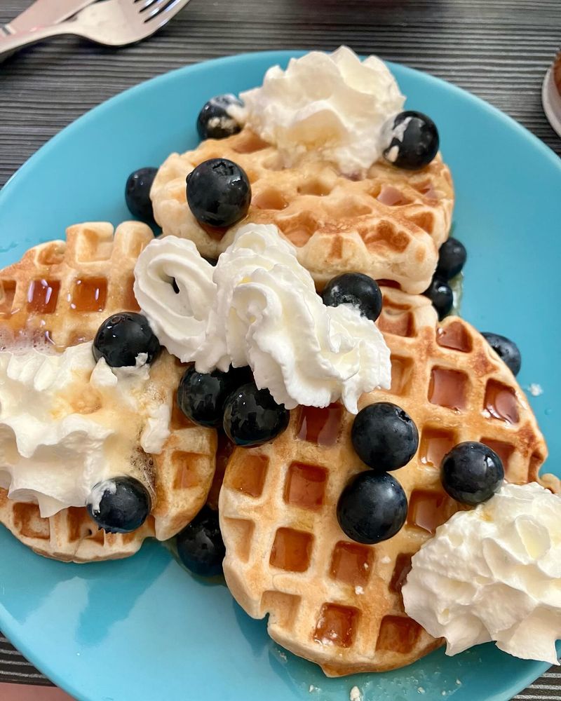 plate of very small waffles with berries, syrup and cream