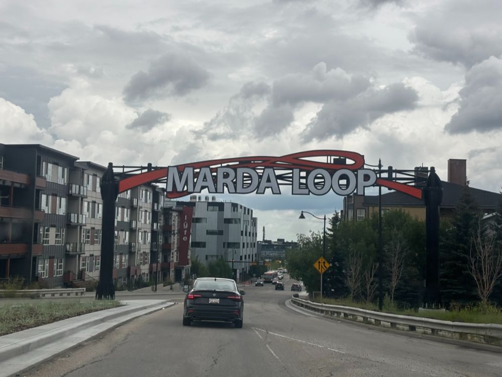 Sign above the roadway that reads "Marda Loop"