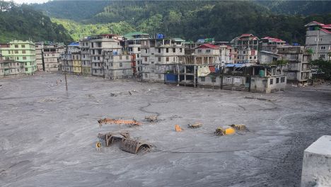 Photograph showing automobiles and buildings buried under the sediments deposited by the flood cascade at Rangpo. Photo credits: Praful Rao 
