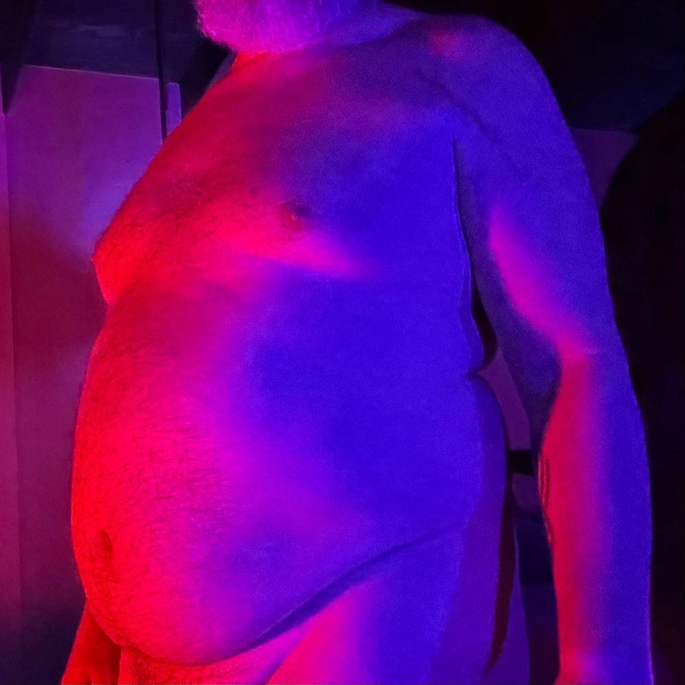 My naked torso showing off my belly at 3/4 a angle with red and blue lighting