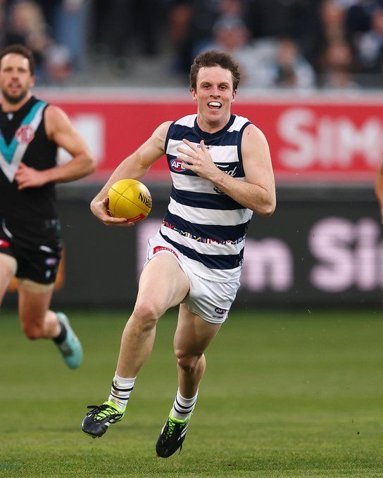Max Holmes. A curly haired footy player runs down the field.