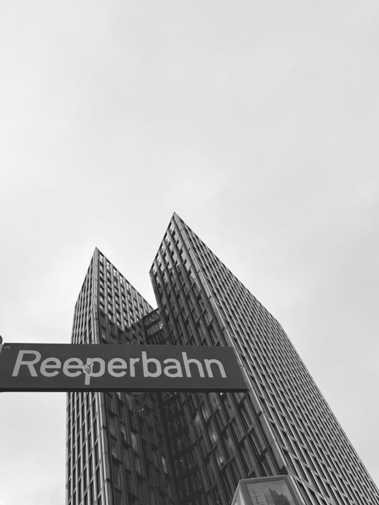 Die Tanzenden Türme mit einem Straßenschild „Reeperbahn“ davor. s/w-Aufnahme, Froschperspektive.