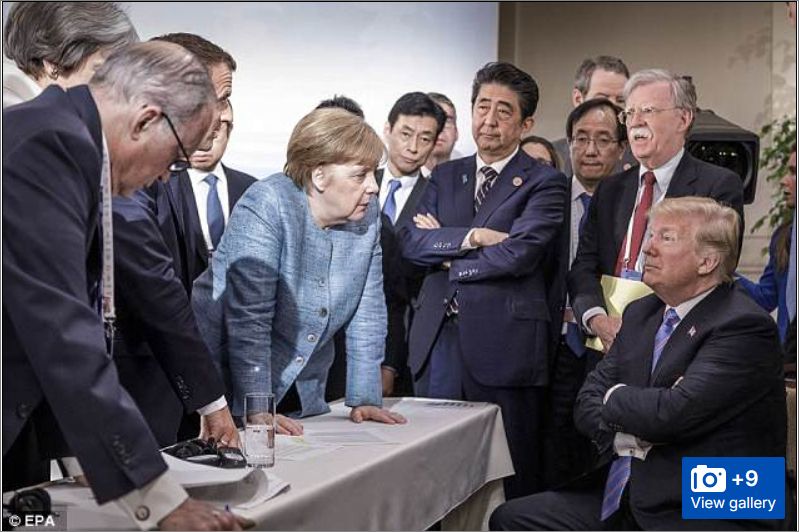 2018 G7 meeting. TACO is sitting at a table, arms crossed, smug look. Opposite him, standing around the table are world leaders with 