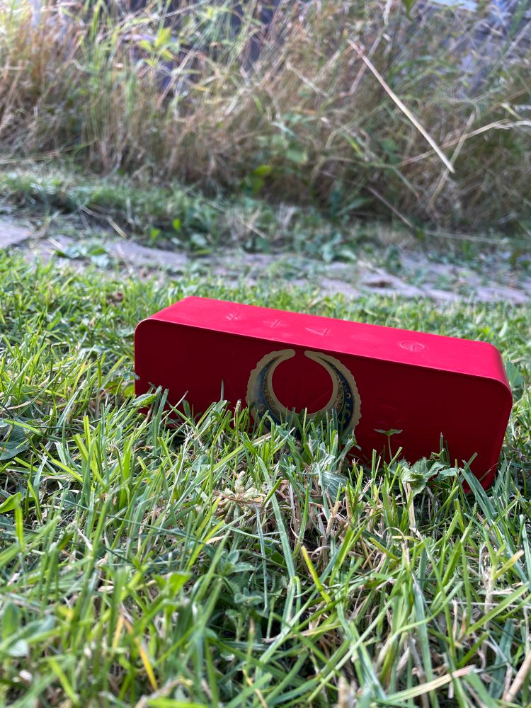 Rote Bluetooth Box in grüner Wiese 
