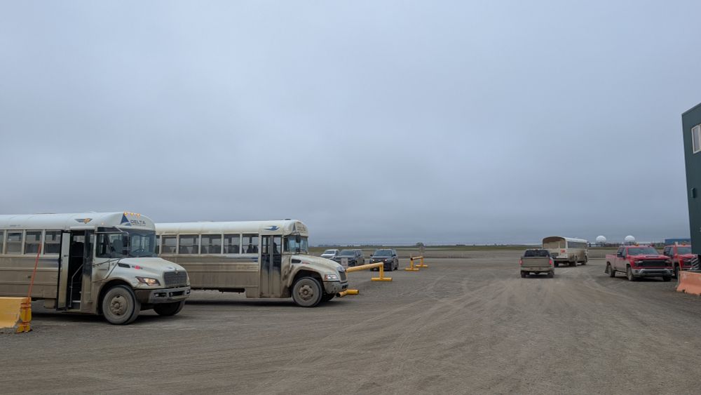 Dirty busses in the SCC gravel lot with he barren oil fields behind.