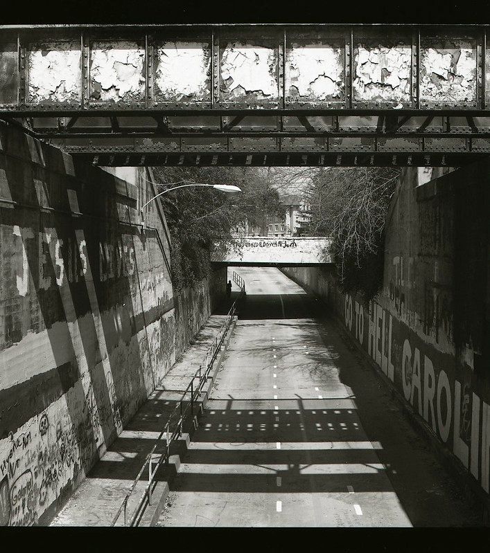 A bridge over a grafitti'd road. Black and white. 