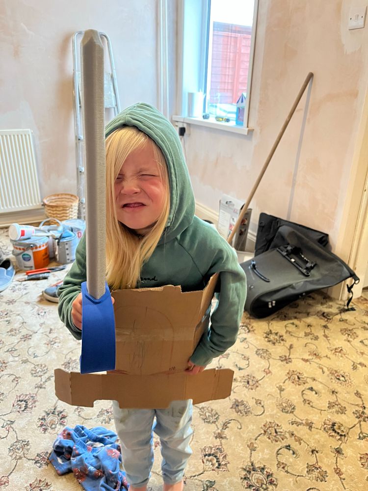 My daughter wearing cardboard armour and menacing me with a sword