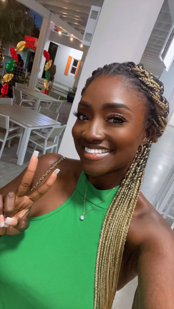 Girl in green top smiling with peace fingers 