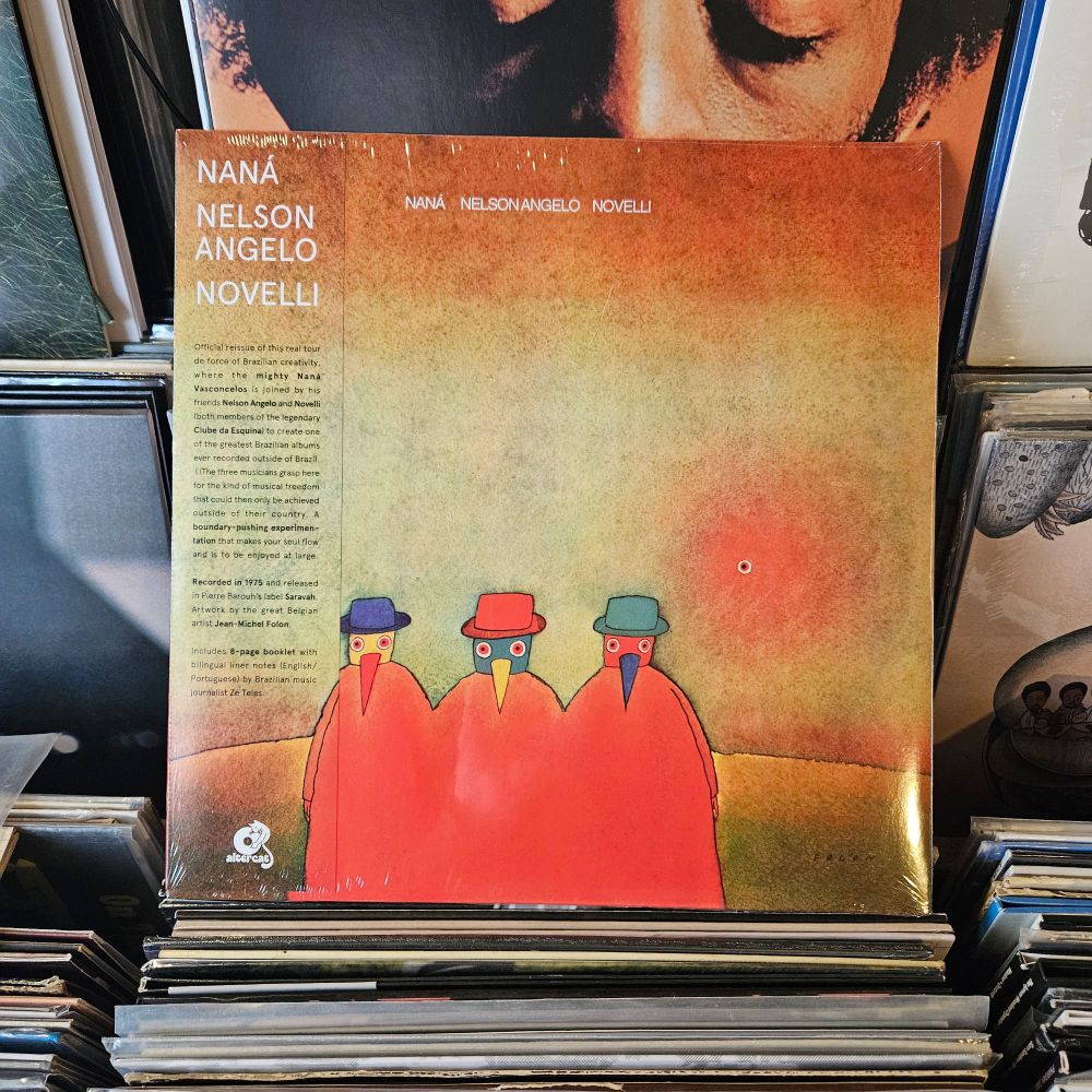 Album cover features an illustration of three multicolored bird men with beaks, all wearing hats, and clothed in a kind of large red smock that seems to cover them all. In the background is a green horizon and orange sky.
