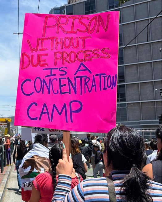 Person holding sign that says "prison without due process is a concentration camp"