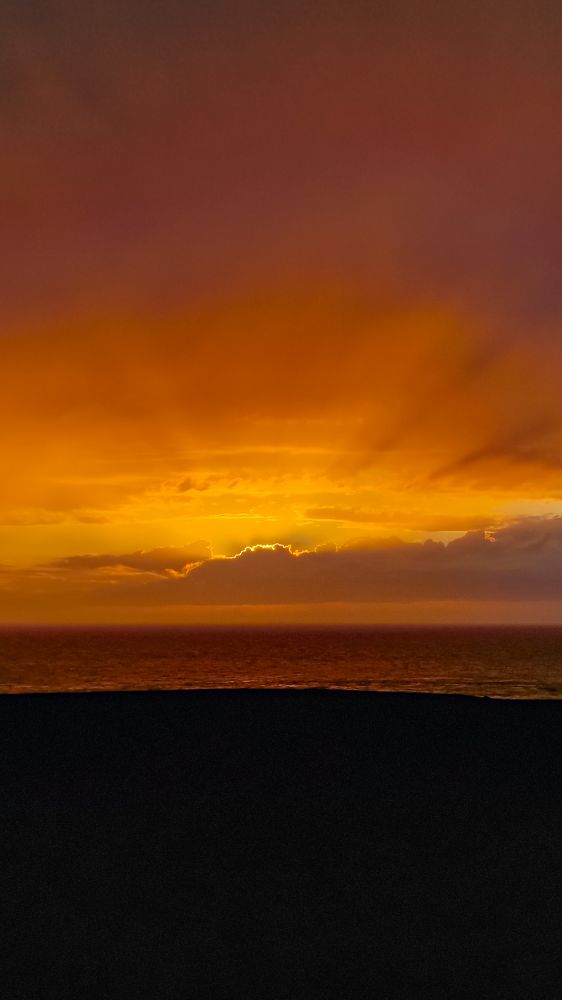 A golden sunset across the sea. Sunbeams make shadows through the clouds like a giant fan. 