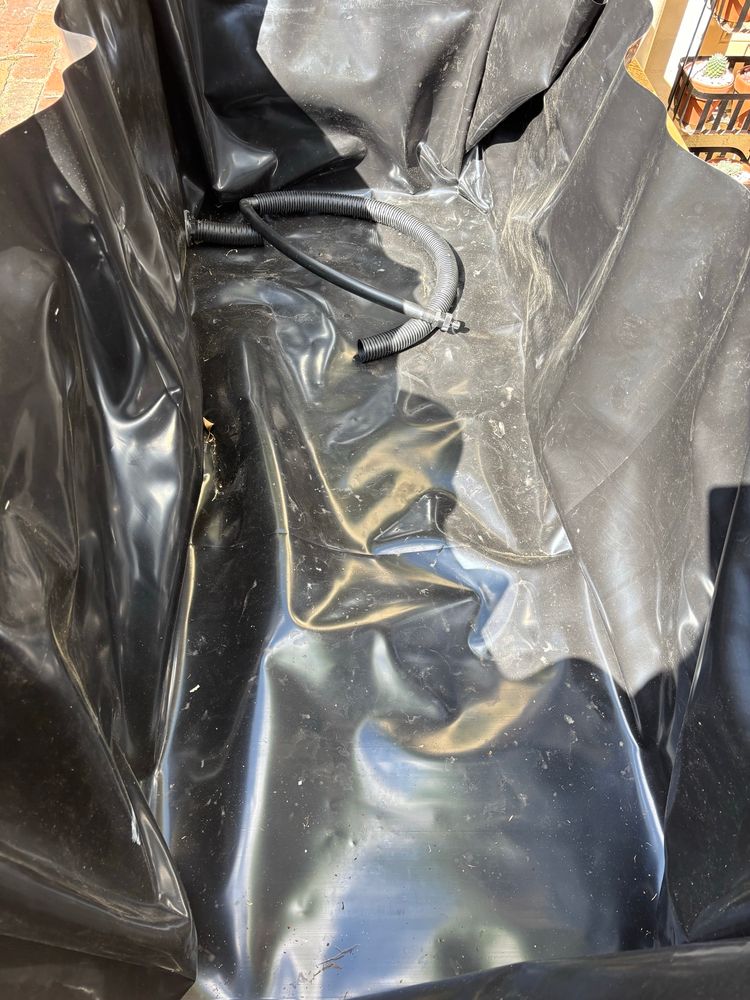 The internals of one wicking bed - it is lined with water safe plastic sheeting. At one end it has the “plumbing” for the wicking bed.