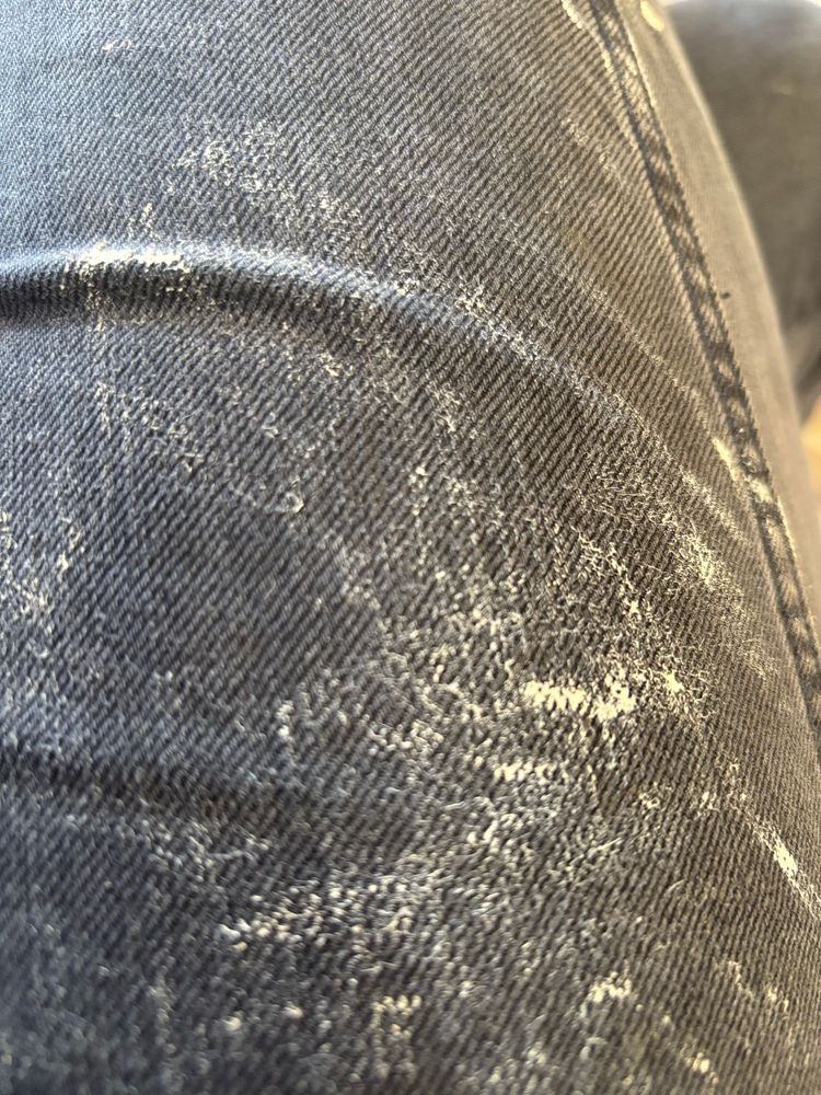 Streaks of pale cream paint on a pair of black jeans 