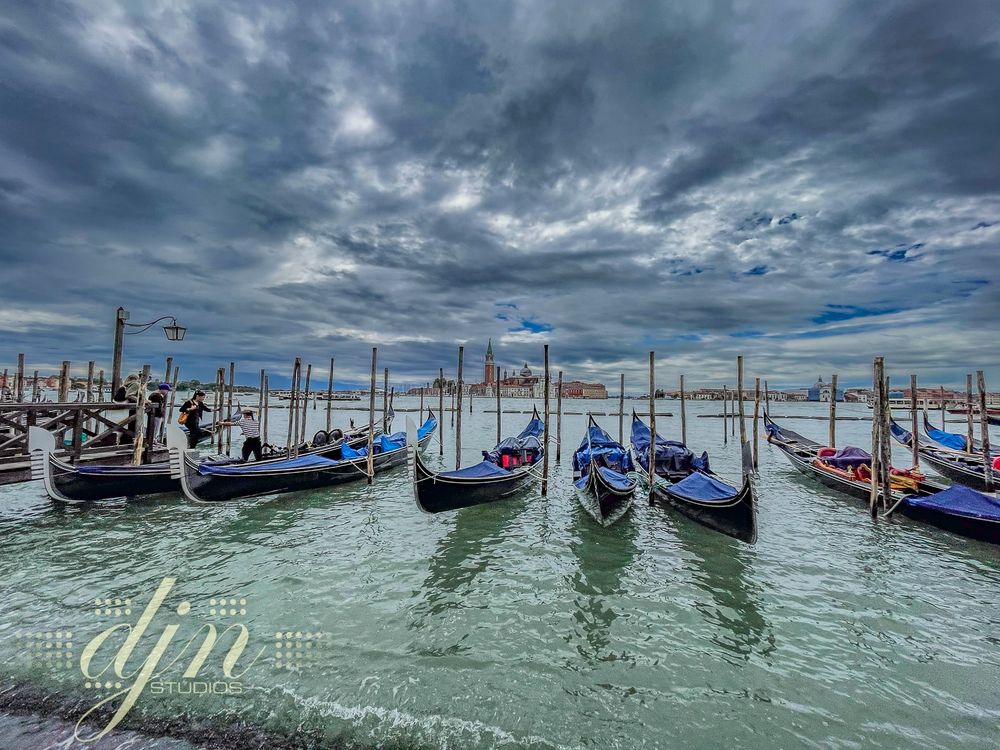Several gondola sit, parked and awaiting passengers to carry through the historic waterways of Venice, Italy. 