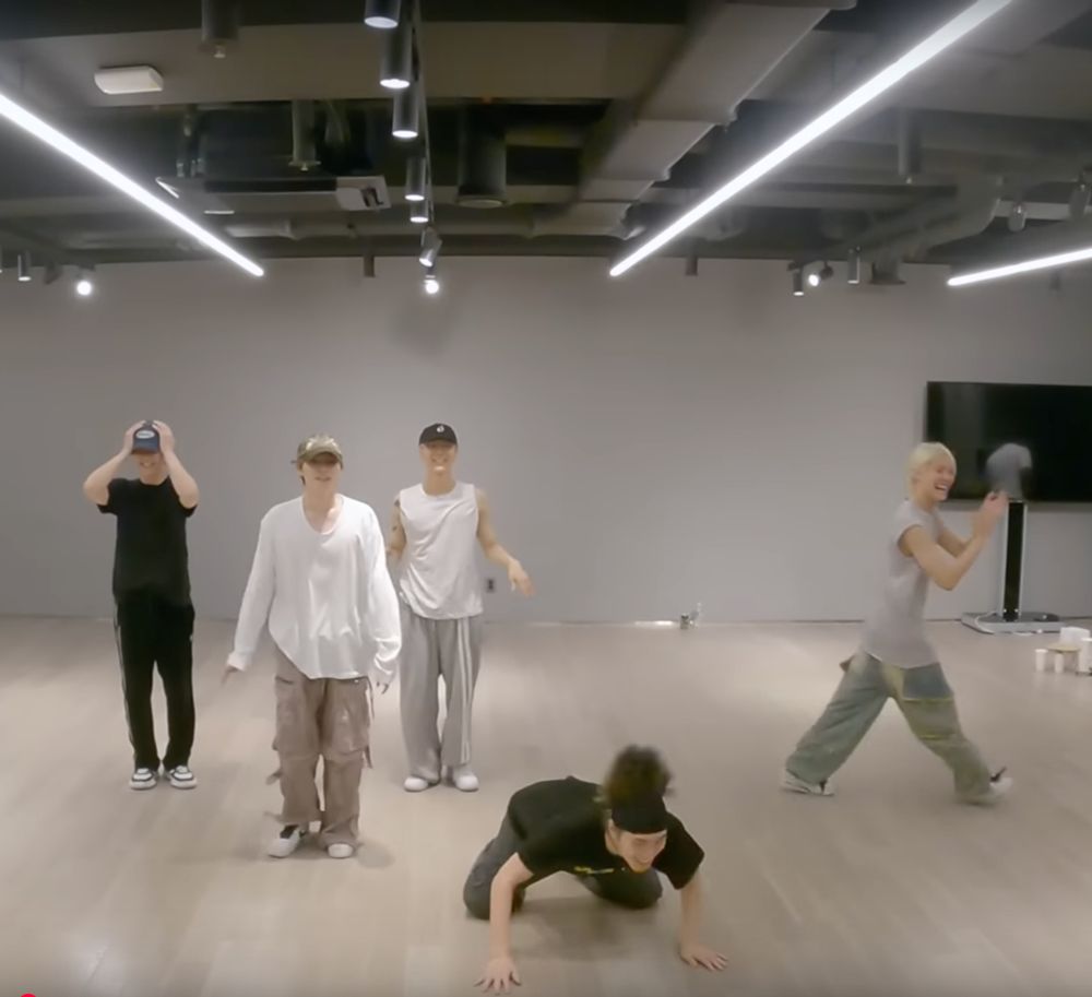 screenshot from WayV's Big Bands/Ice Tea dance practice behind. WayV have all, as a group, just messed up the choreo. Xiaojun and Ten are laughing and trying to correct themselves on the choreo, Kun is head in hands smiling/grimacing, Yangyang is walking away, laughing and clapping. And Hendery is crouched on all fours on the floor, whipping his head back and forth. He looks slightly possessed.