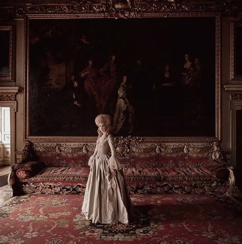 Marisa Berenson as Lady Lyndon in Barry Lyndon. She wears a simple ivory coloured rococo dress with lacy cuffs and only a small wig. Behind her is a long ornate sofa and a huge painting that covers the wall