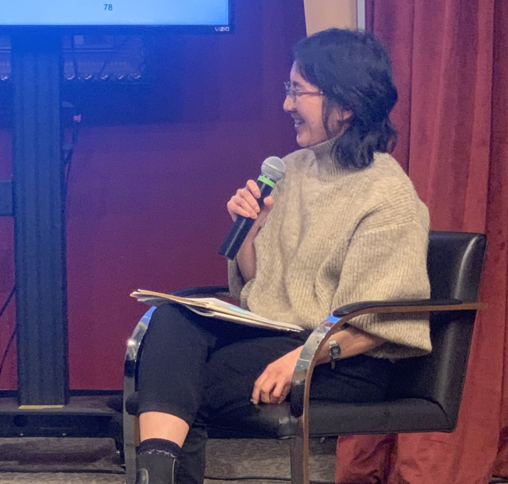 Prof. Anita Say Chan in Q & A discussion following her lecture, she is seated and is holding a microphone.