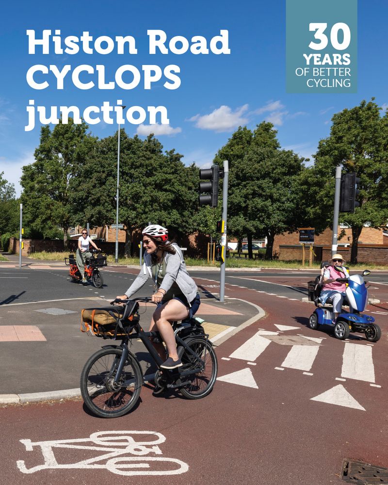 Two cyclists and a mobility scooter user riding around the CYCLOPS protected junction on Histon Road in Cambridge on a blue-sky day. Overlaid is a '30 years of better cycling logo' and the text 'Histon Road CYCLOPS junction'