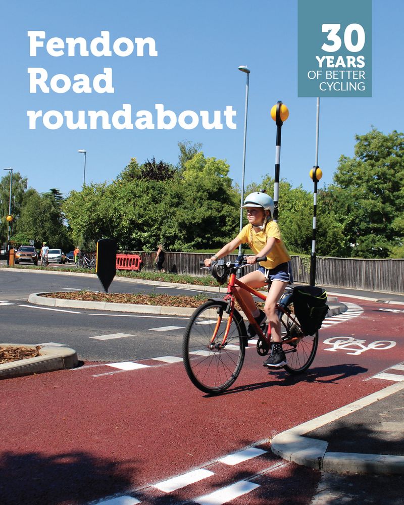 A child in a yellow T-shirt and light blue cycle helmet rides around the Dutch-style roundabout at Fendon Road. Overlaid is a '30 years of better cycling' logo and the text 'Fendon Road roundabout'