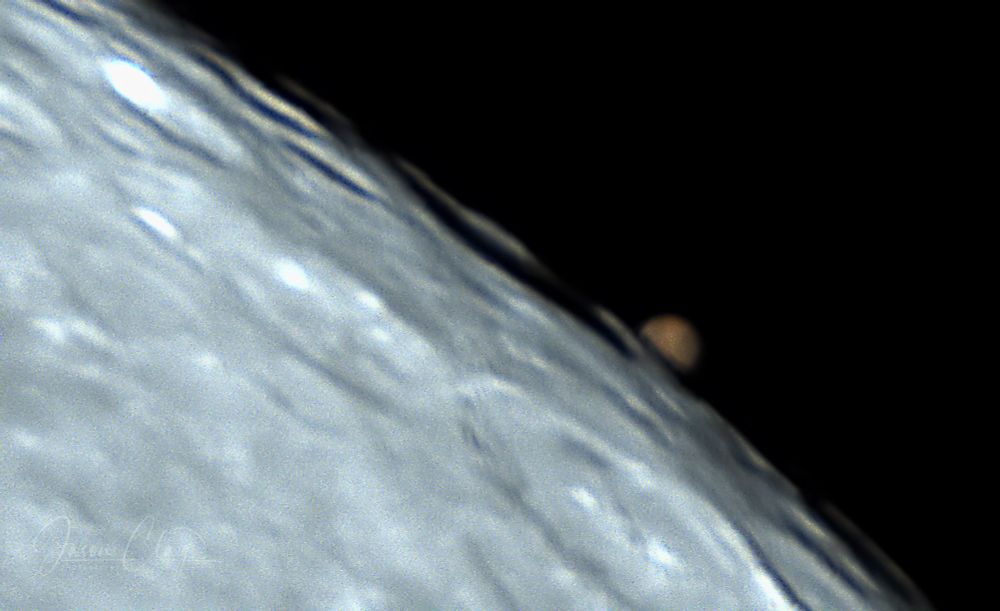 An image of Mars half-covered by the edge of the Moon. 