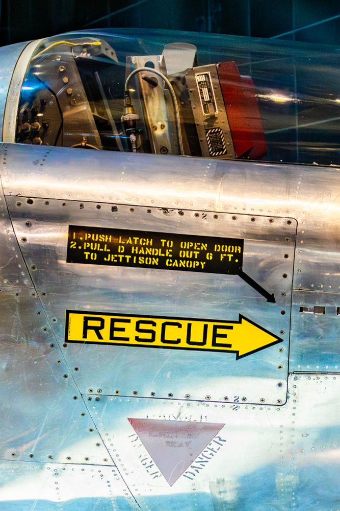 A stainless steel test aircraft with rivets and warning signs. 