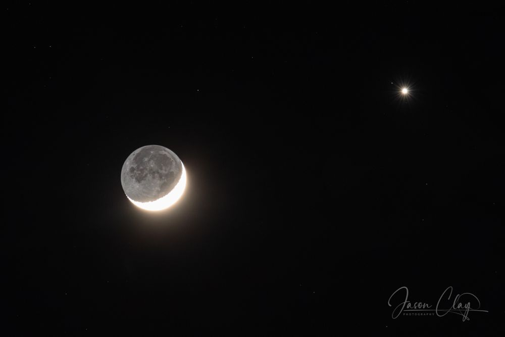 The crescent moon, over-exposed to reveal the features in the shadowed side of the moon. Beside it is a bright pinpoint of light, that resembles as star, but is actually the planet Venus. 