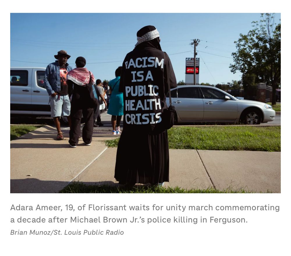 Adara Ameer, 19, of Florissant waits for unity march commemorating a decade after Michael Brown Jr.'s police killing in Ferguson.

Adara is in all Black with FACISM IS A PUBLIC HEALTH CRISIS written on her back. She has a Keffiyeh on her head. 