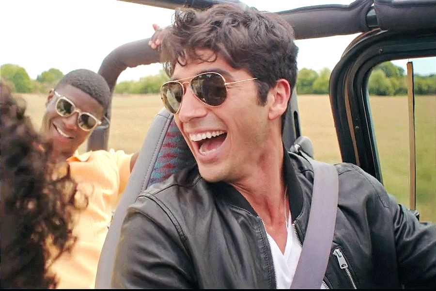 A man in a leather jacket driving and laughing 