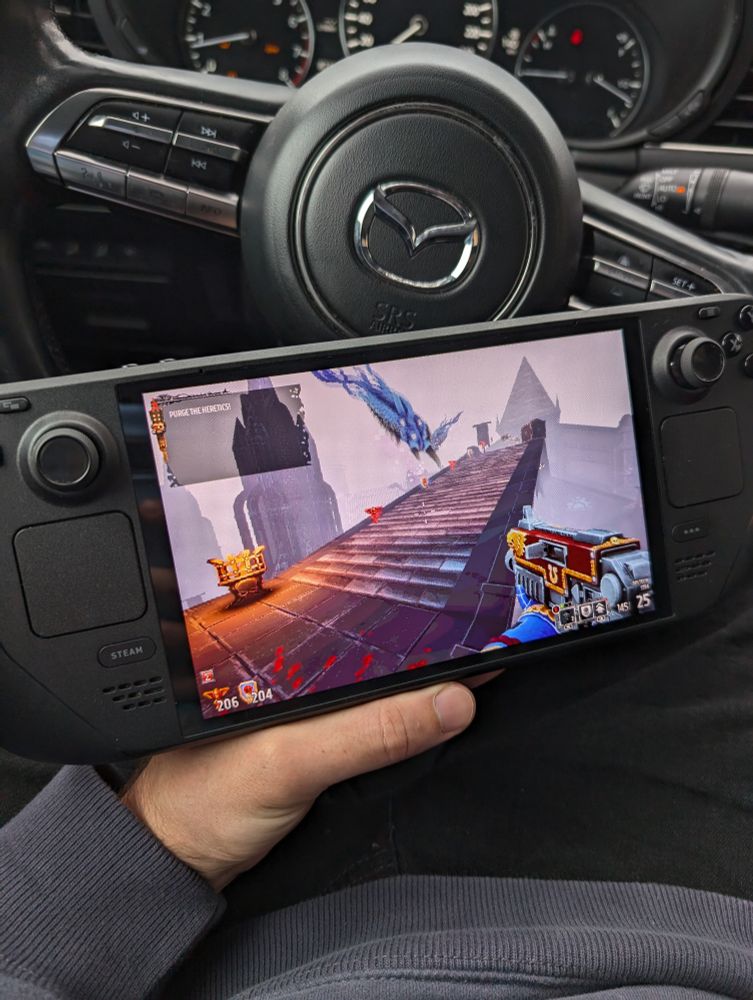 my hand holding steam deck in car with boltgun on it