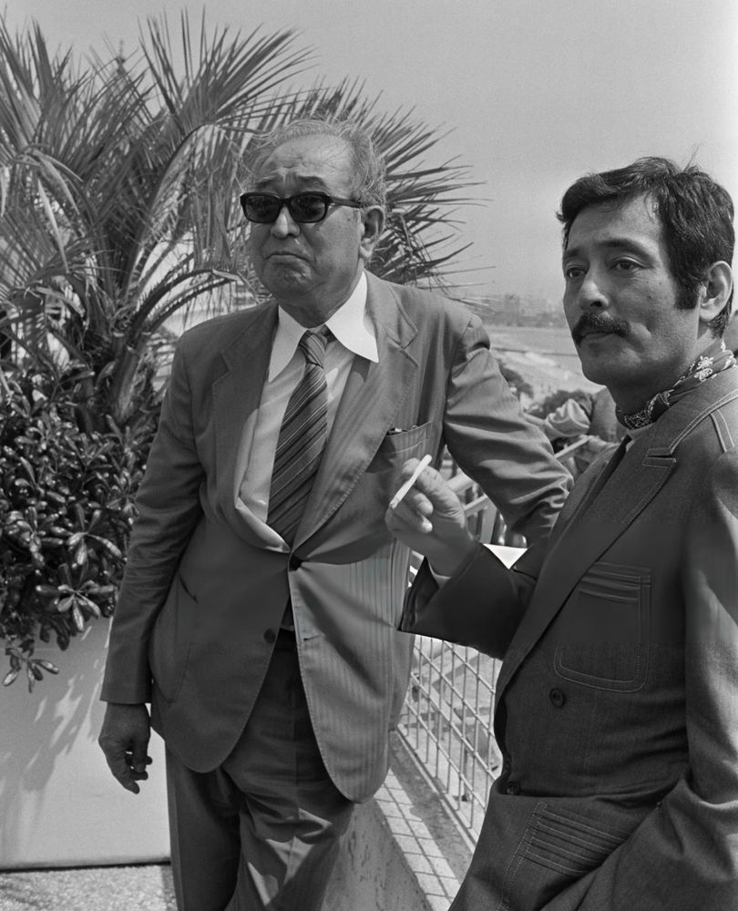 b&w still of nakadai smoking beside kurosawa, both in suits 📽️