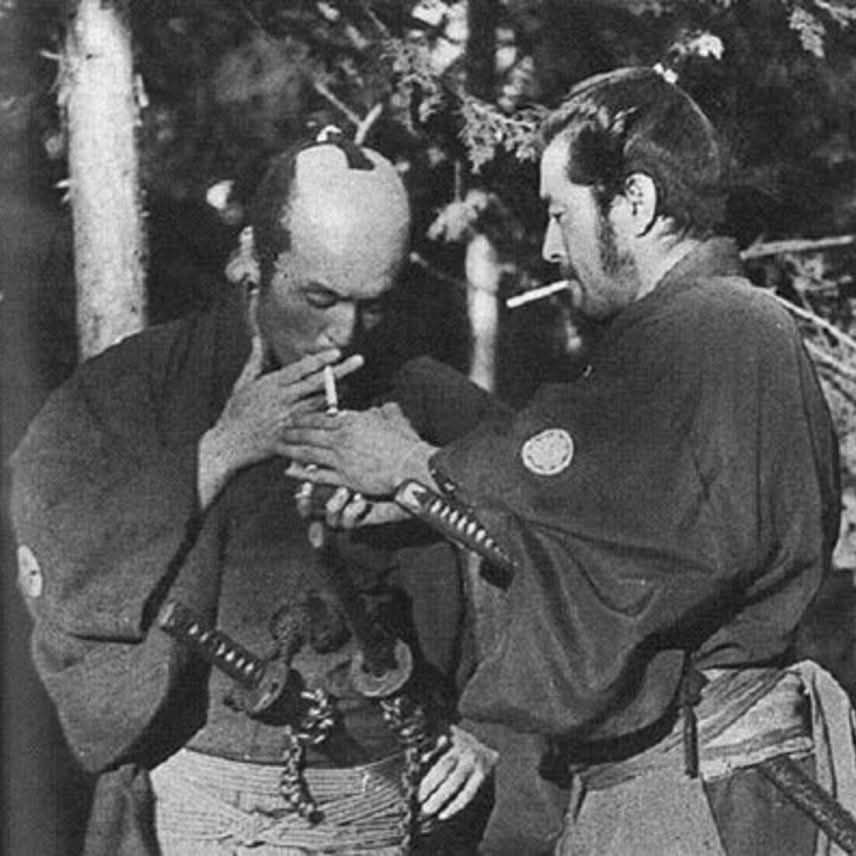 bts still from sanjuro (1962), mifune lighting a dart for nakadai 📽️
