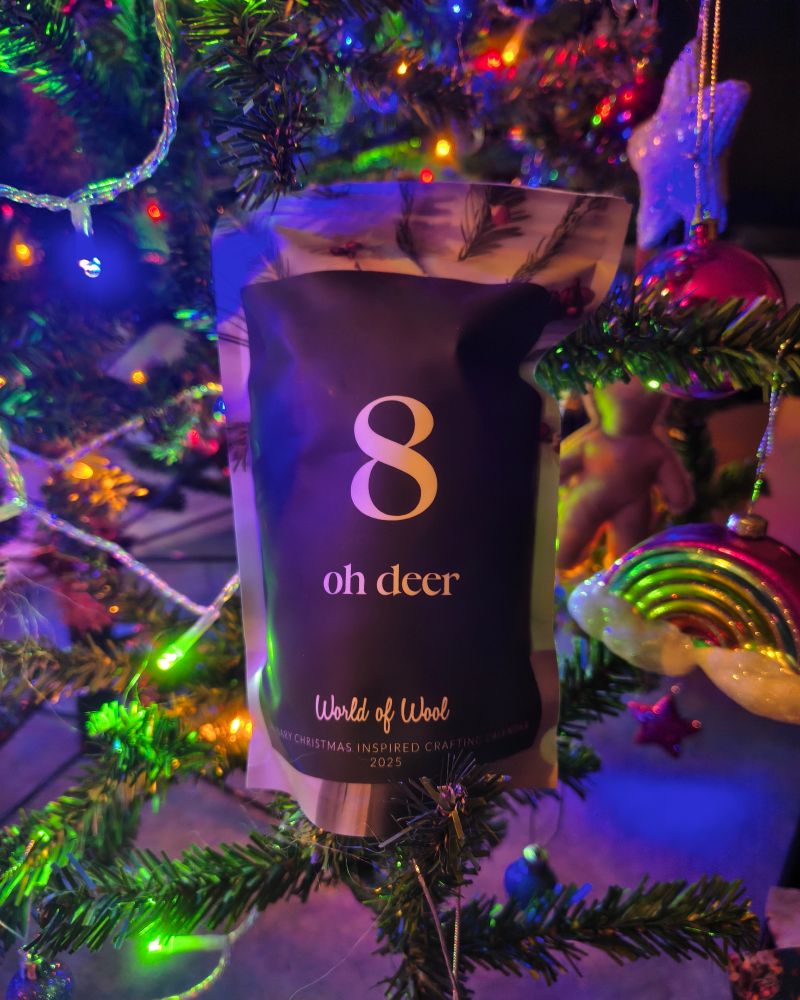 a greyish bag sits in a christmas tree surrounded by lights and ornaments, it has a large 8 and says oh deer