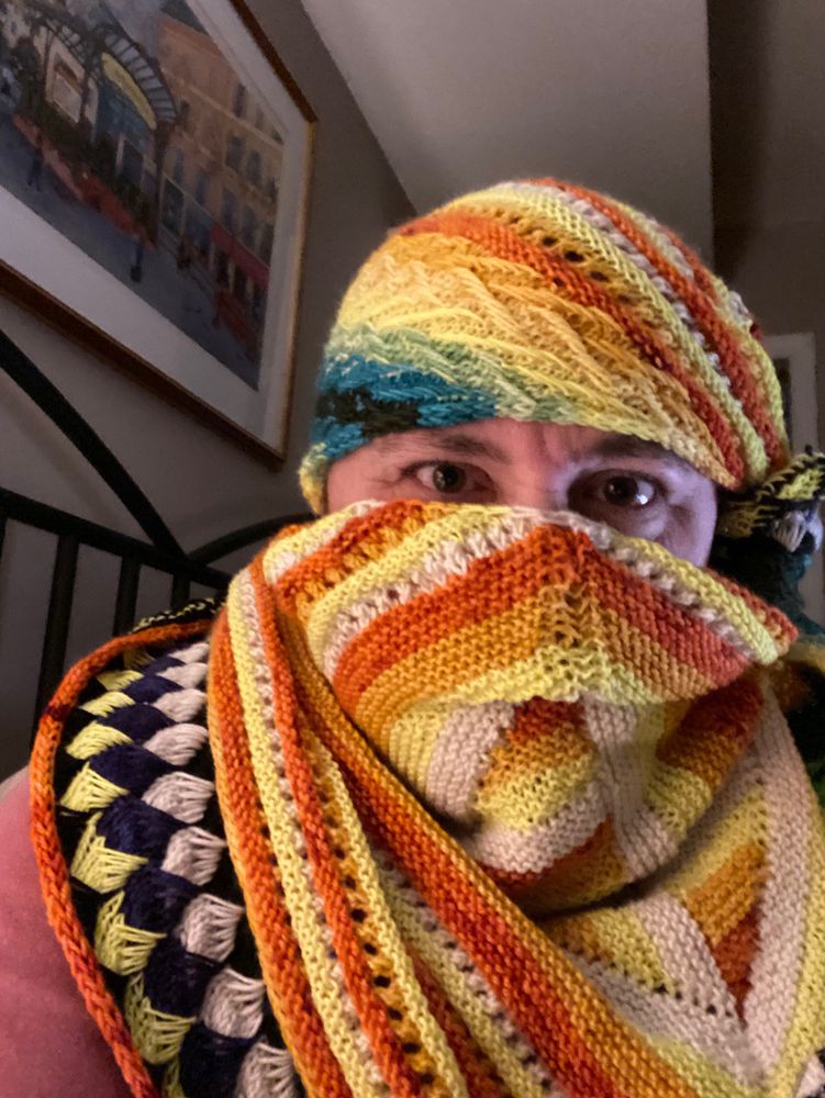 Me wearing a very brightly coloured rainbow / orange / neon yellow shawl wrapped around my head and neck like a very unsubtle ninja