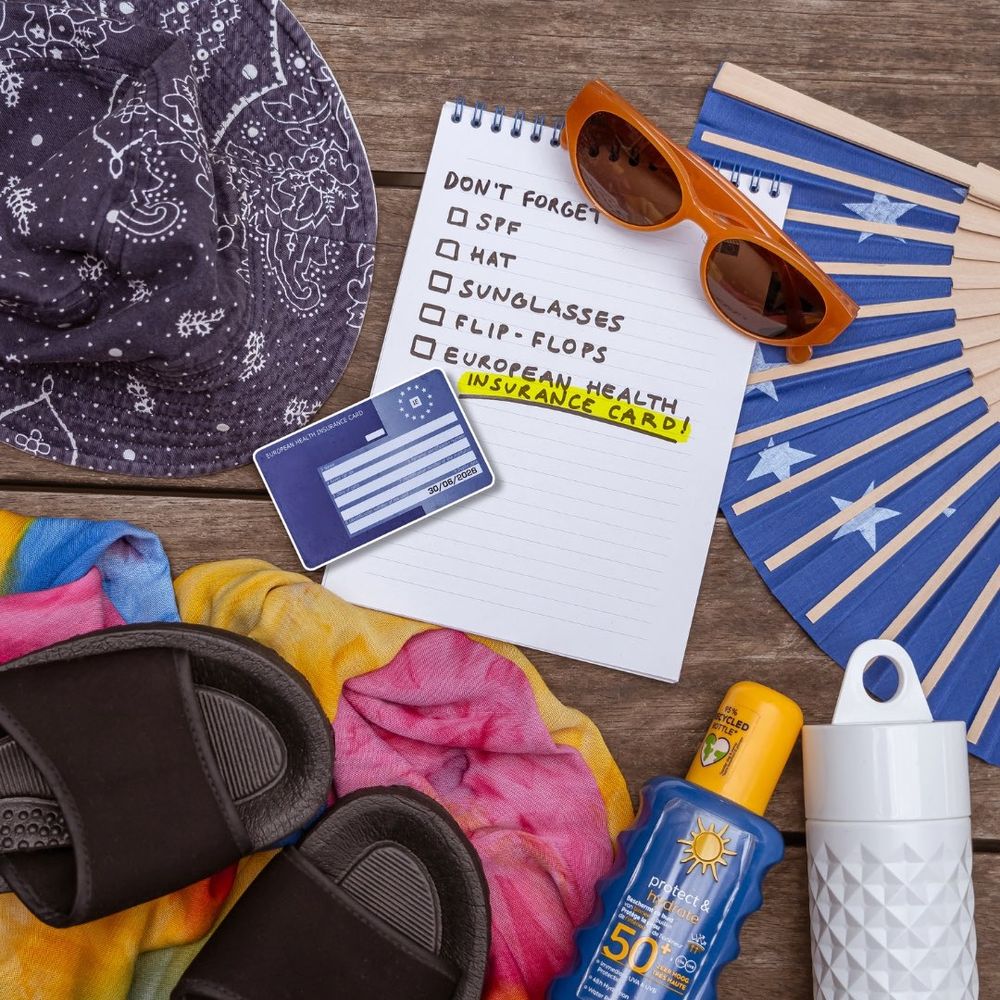 A photo of a European health insurance card, summer shoes, a hat, a bottle of sunscreen, a water bottle, sunglasses and a don't-forget list of summer essentials.