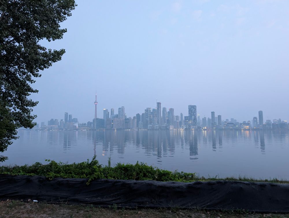 Colour photograph of the Toronto skyline. Smoke fills the sky. The city looks like it's in fog. 