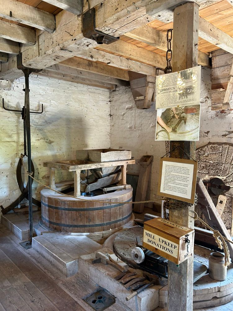 Inside the water mill. Lots of cogs, wheels, belts and grinding stones.