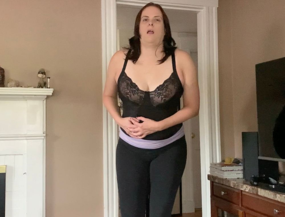 Angelique in all black clutching at her belly as she acts out a scene where she is shot.