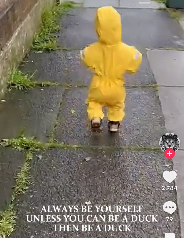 A video still of a child in a full yellow rain suit running on a wet sidewalk, and the text says, “ALWAYS BE YOURSELF. UNLESS YOU CAN BE A DUCK. THEN BE A DUCK.”