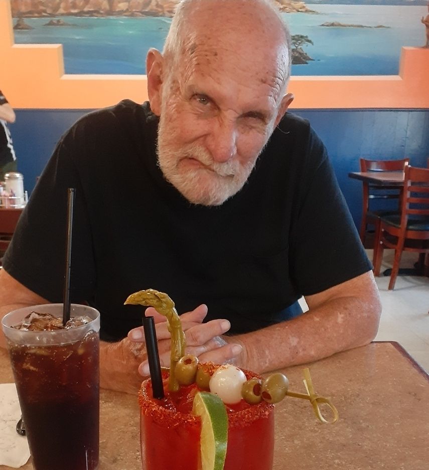 83 year old, bald, snarling Uncle sitting at a café table. 