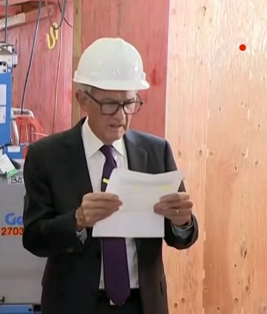 Fed Chair Powell looking at a sheet of paper handed to him by Trump.