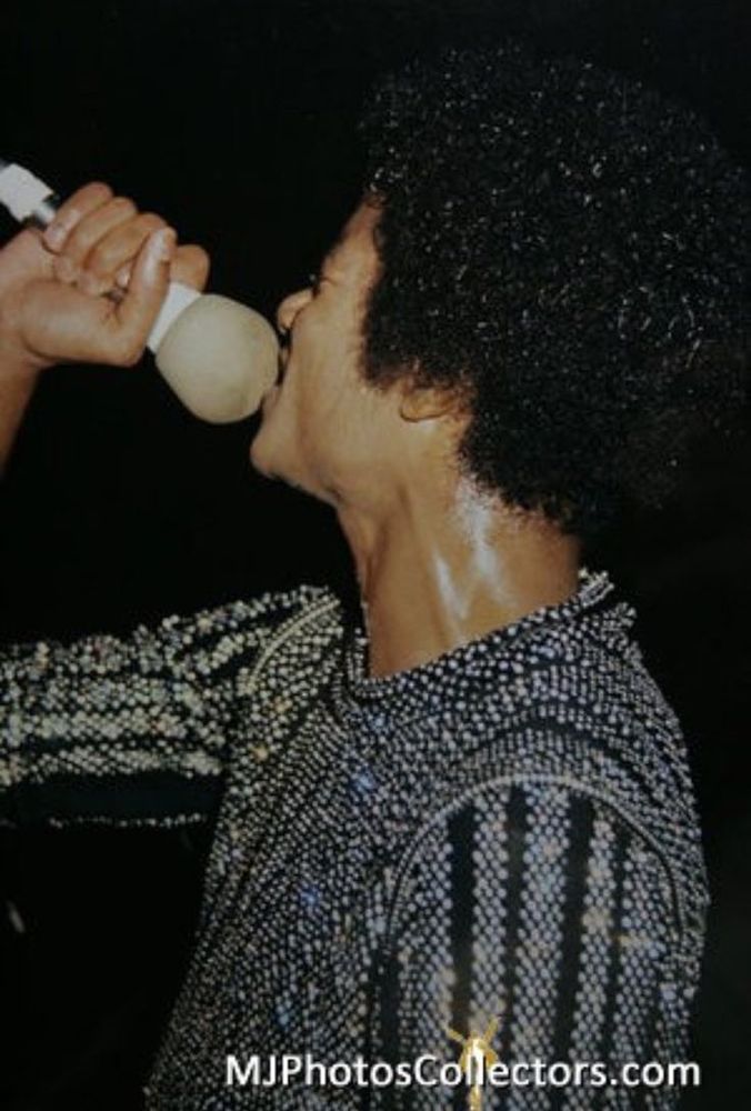 A photo of Michael Jackson performing during the Triumph Tour wearing a rhinestone-covered top and his hair in a short curly afro.
