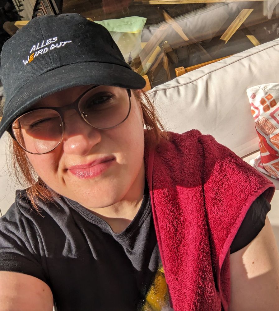 Selfie of my sunlit face with a baseball cap and of course a red towel slung over my shoulder.