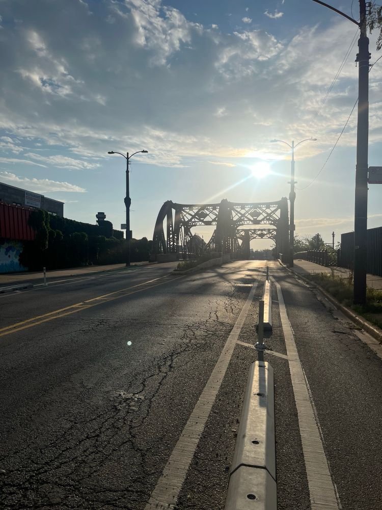 The sun rises over an empty road.  Bridge in the distance.  